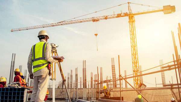 a man in a safety vest and helmet standing at a construction site